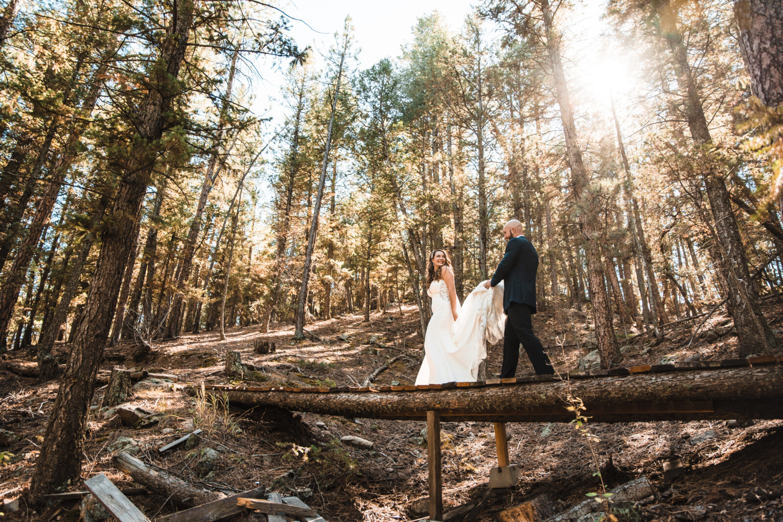 My family doesn't want me to elope blog header. Eloping couple walking across a log bridge in the Colorado forest.